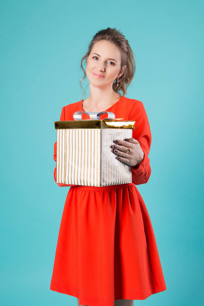 girl with a gift in a red dress on a blue backgroun - Foto, imagen