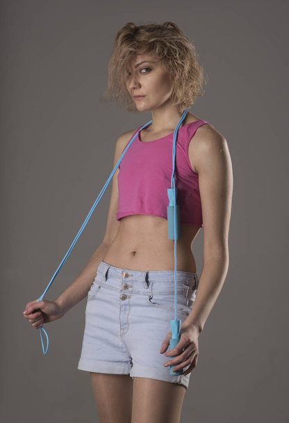 Woman coach with cunning face holds jump rope - Fotografie, Obrázek