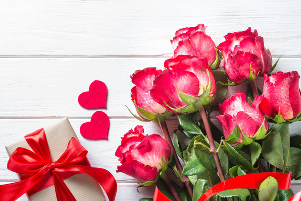 Красный цветок розы и коробка подарков на деревянном столе
.  - Фото, изображение