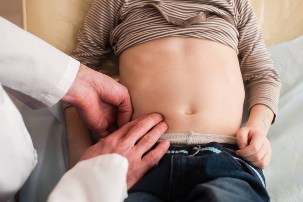 Pediatra revisa estómago del niño
 - Foto, imagen