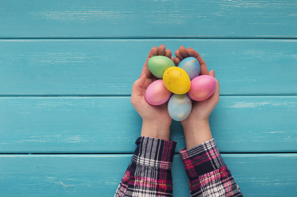 Mujer sosteniendo coloridos huevos de Pascua en tablones de madera
 - Foto, imagen