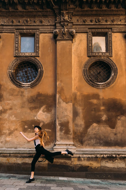 Mädchen in schwarz-weißer Kleidung springen als Ballerina über den Bürgersteig - Foto, Bild
