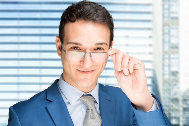 Smiling businessman holding his eyeglasses - Fotó, kép
