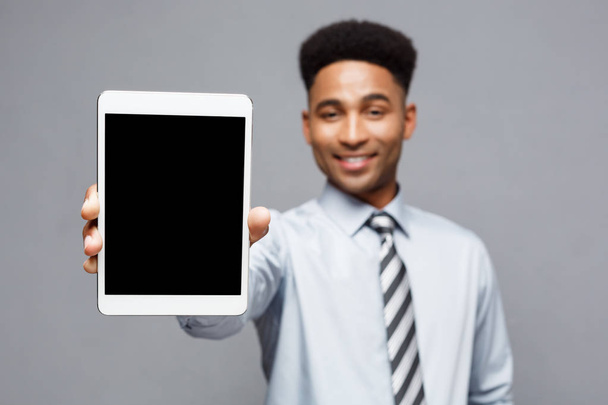 Business Concept - Щасливий красивий професійний афроамериканський бізнесмен, що показує цифровий планшет клієнту
. - Фото, зображення