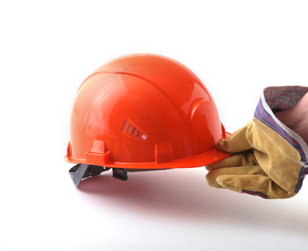 worker in protective gloves holds an orange hard hat in his hand. Safety helmet. - Foto, Imagen