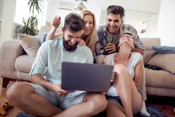 Group of friends enjoying time together and looking movie on laptop. - Foto, imagen