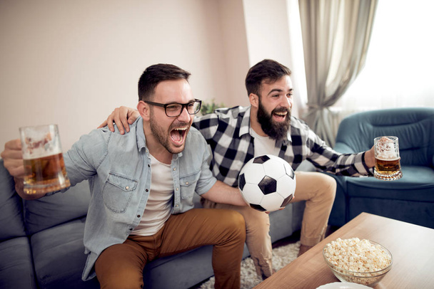 Amistad, deporte, personas y concepto de entretenimiento- aficionados al fútbol viendo fútbol en la televisión en casa
. - Foto, Imagen