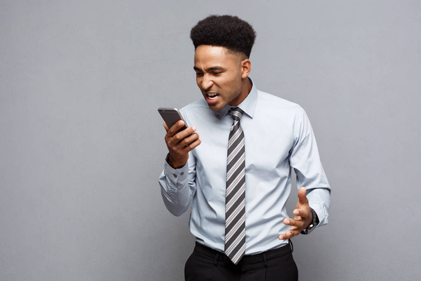 Businessconcept - stressvolle Afro-Amerikaanse zakenman schreeuwen en schreeuwen op mobiele telefoon. - Foto, afbeelding