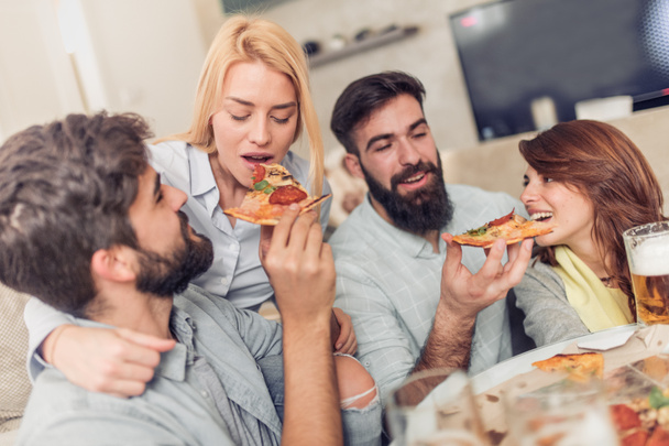 Friends watching TV at home while eating pizza  - Photo, Image