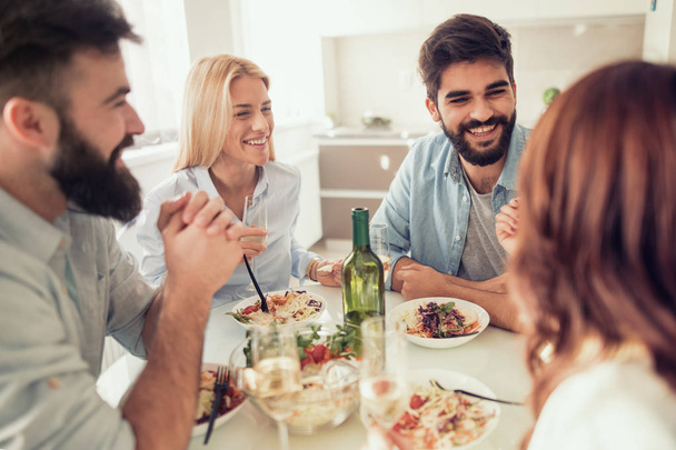Freunde beim Mittagessen zu Hause. Gruppe glücklicher Menschen mit Brille, die sich unterhalten und zu Hause gesunde Mahlzeiten zu sich nehmen. - Foto, Bild