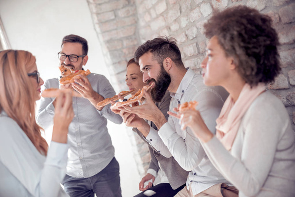 Business, Essen, Mittagessen und Leute, die ein Konzept haben - glückliches Geschäftsteam, das im Büro Pizza isst. - Foto, Bild