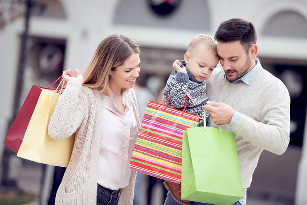 Família feliz com filho pequeno e sacos de compras na cidade.Venda, consumismo e conceito de pessoas
. - Foto, Imagem