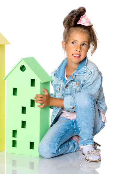 Little girl is playing with wooden houses. - Zdjęcie, obraz