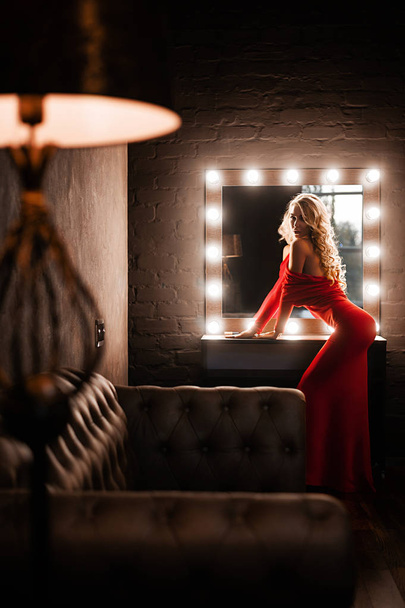 Luxurious woman in red dress posing in the room - Fotó, kép