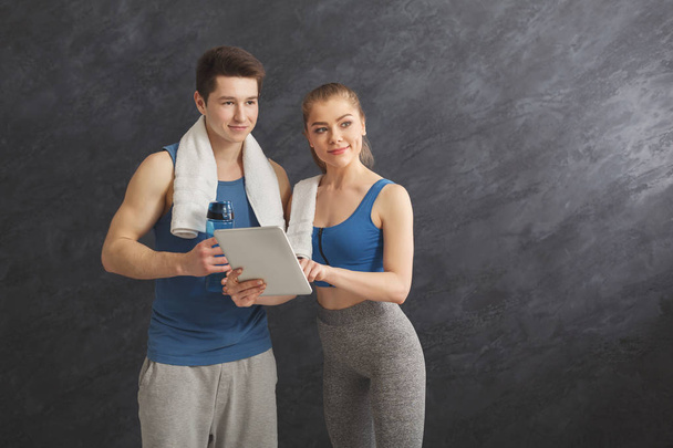 Młoda para omawiając plan treningu w siłowni - Zdjęcie, obraz