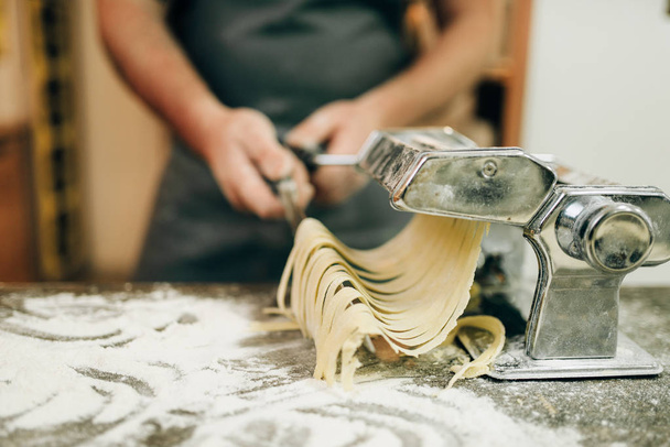 cocinar con cuchillo de cocina fresca fettuccine casero en la máquina de pasta
 - Foto, Imagen