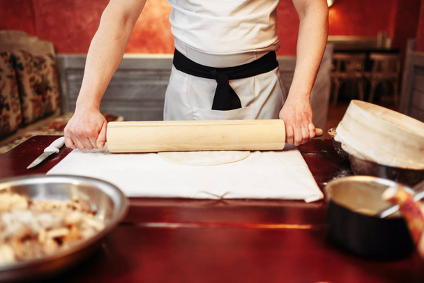 male chef rolling dough with rolling pin - Foto, afbeelding