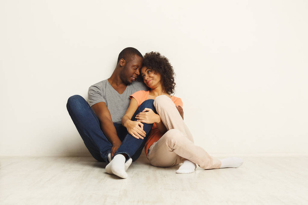 Coppia afro-americana che si abbraccia, seduta sul pavimento
 - Foto, immagini
