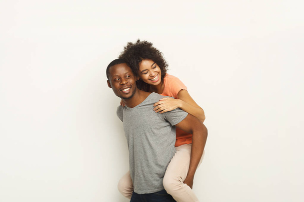 Black man piggybacking girlfriend at white studio - Φωτογραφία, εικόνα