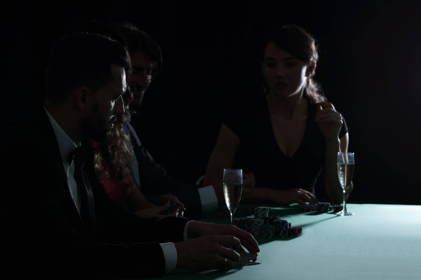 Seitenansicht einer Gruppe von Menschen, die gemeinsam im Casino Poker spielen - Foto, Bild