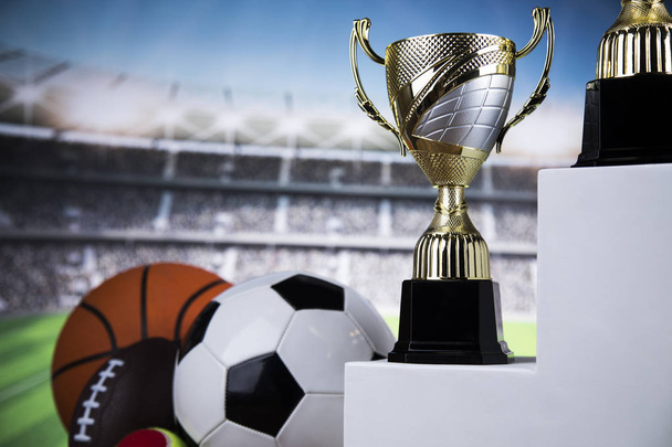 Copas de premios ganadores en podio blanco, fondo deportivo
 - Foto, imagen