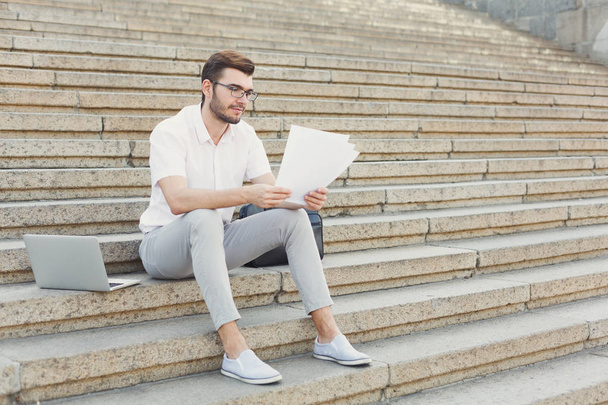 Hombre de negocios pensativo leyendo los documentos al aire libre
 - Foto, imagen