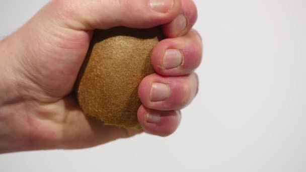 hand squeezes the juice from the kiwi into a glass on a white background - Metraje, vídeo