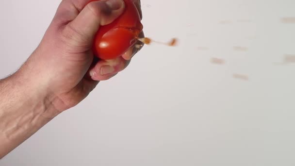 Hand squeezes juice from a tomato - Záběry, video