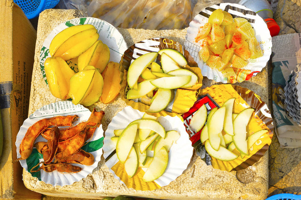 Φέτες Κονκανικά φρούτων, όπως tamarind, amla ή Ινδικό φραγκοστάφυλο, ανεπεξέργαστα μάνγκο και φρούτα αστέρων ή καράμβολες προς πώληση στην παραλία Nagaon  - Φωτογραφία, εικόνα