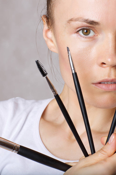 Young caucasian lady is keeping make up brushes kit close to her face. Closeup - Photo, Image