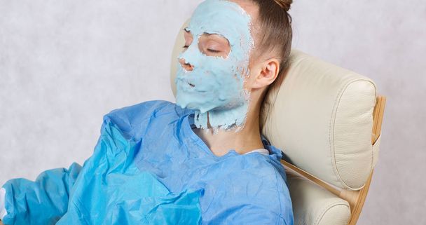 Jonge dame tussen de 30 en 40 jaar oud heeft een gezichtsmasker zitten in cosmetological fauteuil - Foto, afbeelding