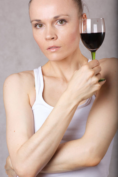 30 ila 40 yaşları arasında genç bayan bir kadeh kırmızı şarap elinde tutar. - Fotoğraf, Görsel