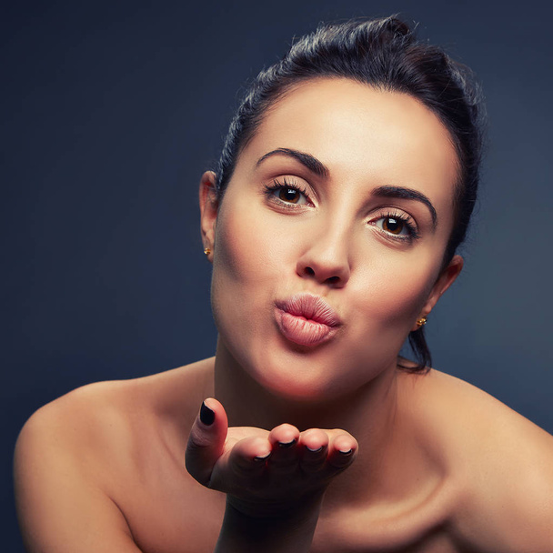 Portrait of woman with natural makeup making air kiss on dark background  - Foto, imagen