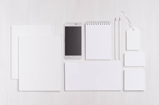 White blank stationery - label, notepad, letterhead, envelop, phone on soft white wooden plank, blank objects for placing your design. Modern stylish work place. - 写真・画像