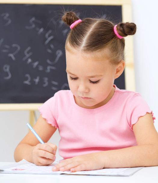 Little girl is writing using a pen - Foto, Bild