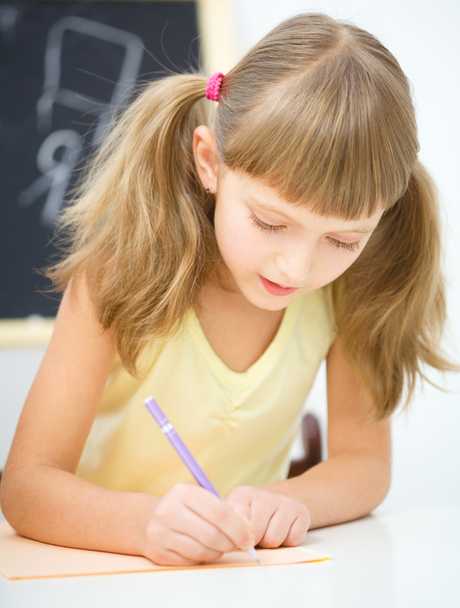 Little girl is writing using a pen - Фото, зображення