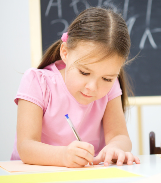 Little girl is writing using a pen - Foto, Bild