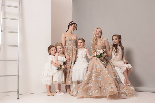 Little pretty girls with flowers dressed in wedding dresses - Fotó, kép