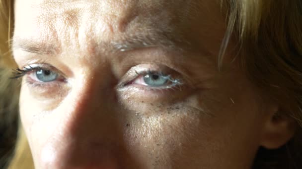 Slow motion close up: Tear comes out of an eye and streaks down the cheek. Sad female with blue painted eyes crying - Video