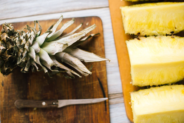 Sliced fresh pineapple on a wooden background in sunlight - Foto, afbeelding