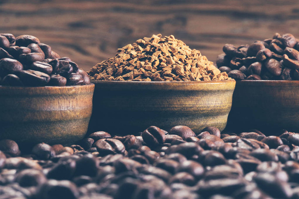 Pila de granos de café y café instantáneo en el fondo de café molido
 - Foto, imagen