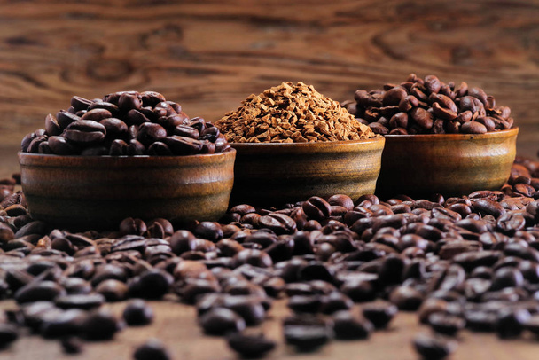 Stapel koffiebonen en koffie direct op de achtergrond van gemalen koffie - Foto, afbeelding