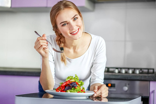Una giovane ragazza sana mangia un'insalata di verdure. Donna in coagulo bianco
 - Foto, immagini