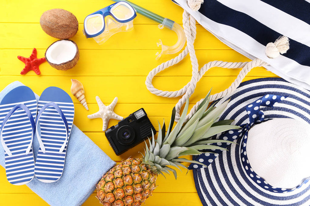 Beach accessories with pineapple on yellow wooden table - Фото, изображение