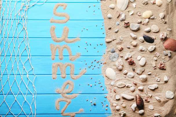 Word summer with beach sand and seashells on blue wooden table - 写真・画像