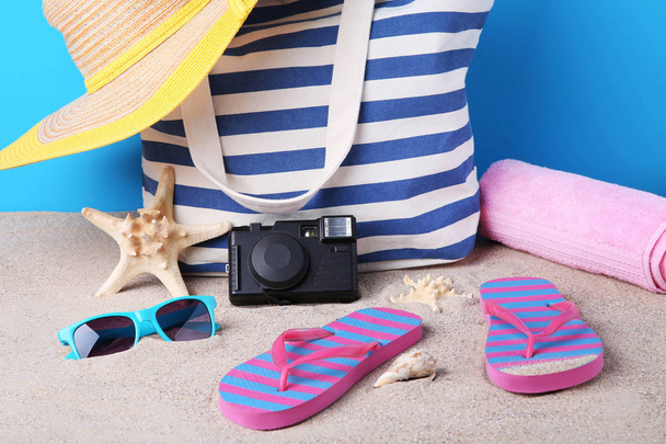 Summer bag with hat, flip flops, camera and starfish on beach sand - Foto, Imagen