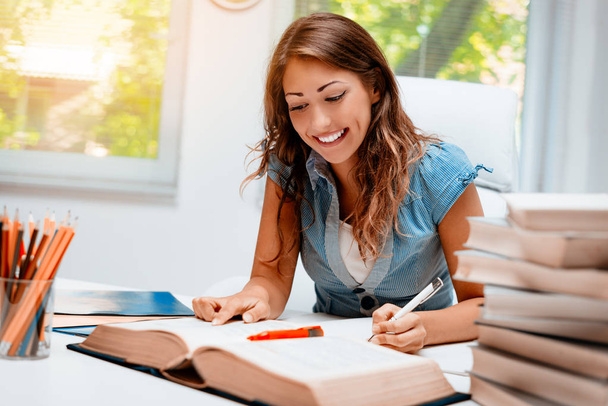 Smiling teenage girl with books learning in library - Φωτογραφία, εικόνα