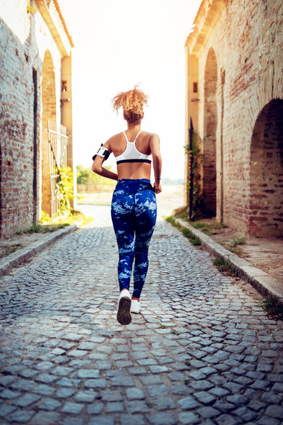 Widok z tyłu fitness młoda kobieta z słuchawki jogging - Zdjęcie, obraz
