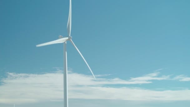 Blauwe hemel windenergie. Een horizontale as wind turbine (Hawt) toren spinnen in de wind op een bewolkte dag. - Video