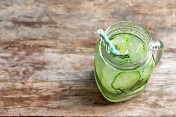 Mason jar of fresh lemonade with cucumber on wooden table - Foto, afbeelding